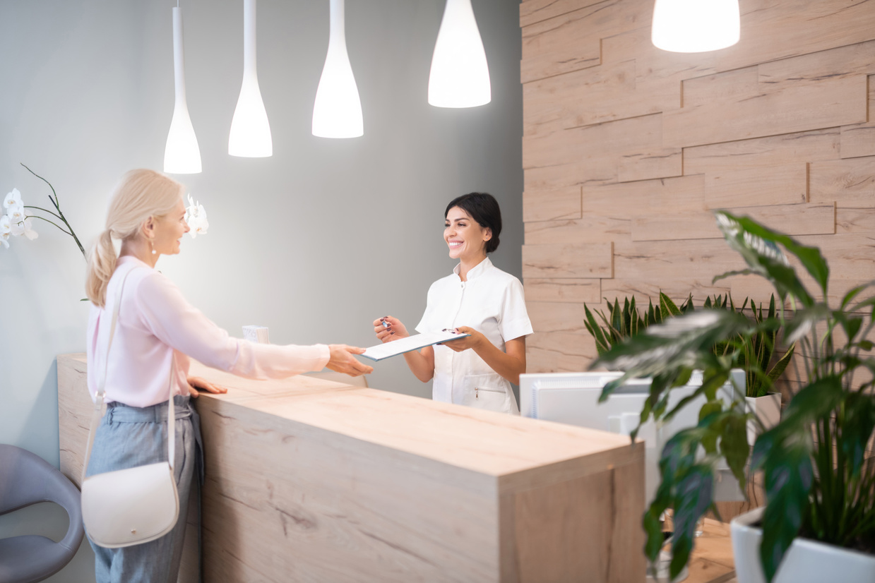 Woman standing at reception of dental clinic.